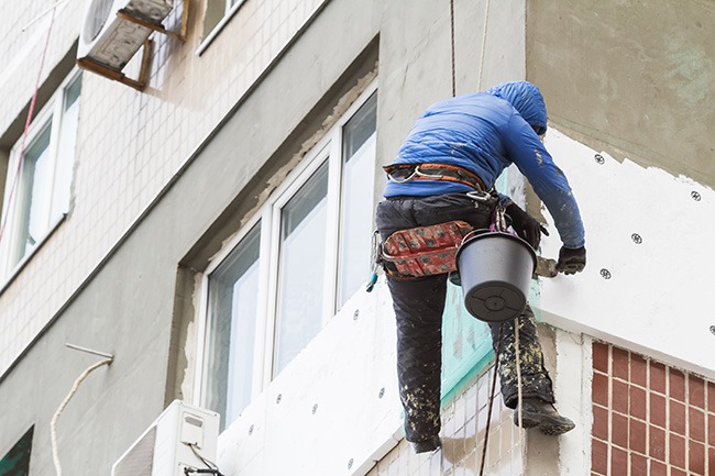 The painter uses a paint roller outside high building